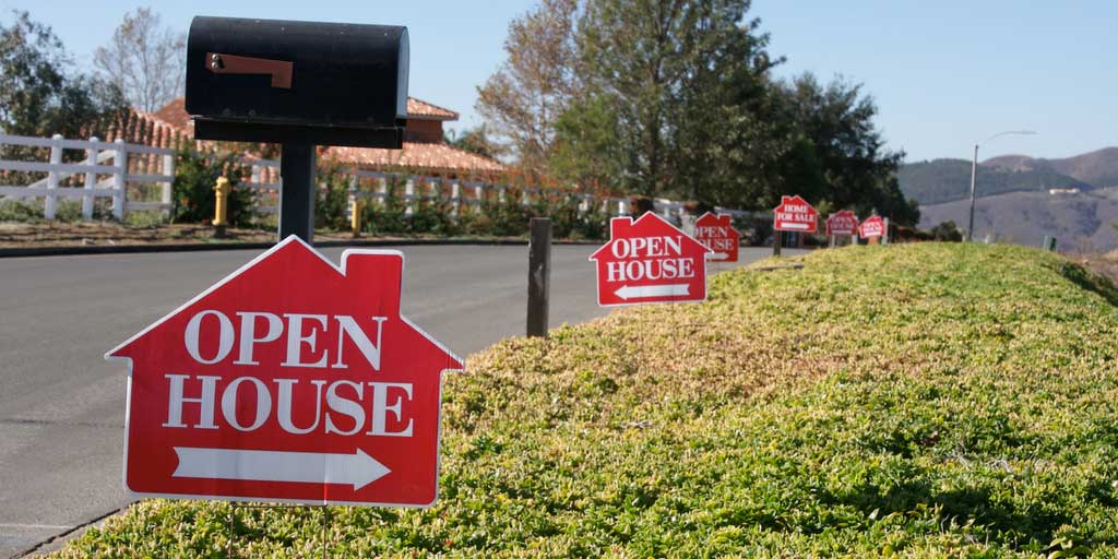 A row of open house signs on the side of a road.